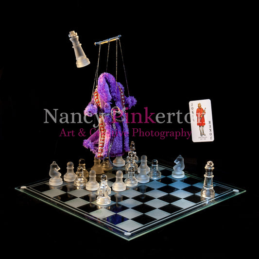 Photographic art print with image of a playing card featuring John Balliol. a purple robe hanging from puppet strings and king piece floating above a glass chessboard with chess pieces arranged in a square.